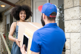 Delivery driver handing a package to a smiling customer at a pickup point, symbolizing convenience and trust in the last mile experience.